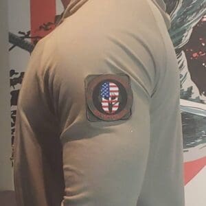 A Modern Warrior Project Patch: Spartan Wearing Headset wearing a tan shirt with an American flag and a Spartan headset.