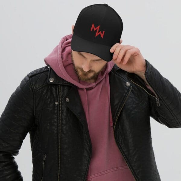 A man in a black leather jacket and a Modern Warrior Flex Fit Structured Twill Cap with an M on it.