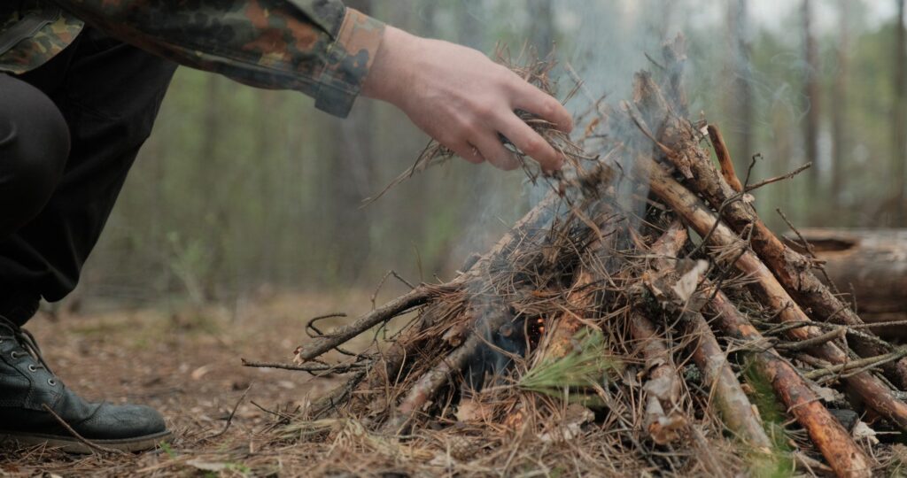 Low angle shot of a man is trying make a fire in the forest.