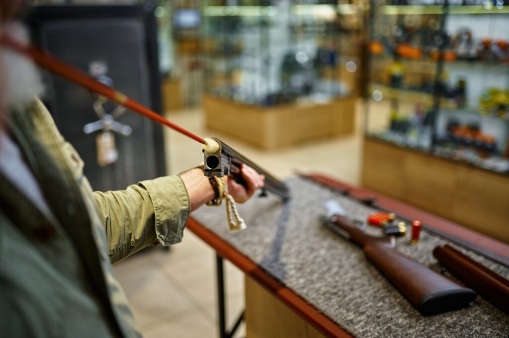 Male hunter with ramrod cleans rifle in gun store