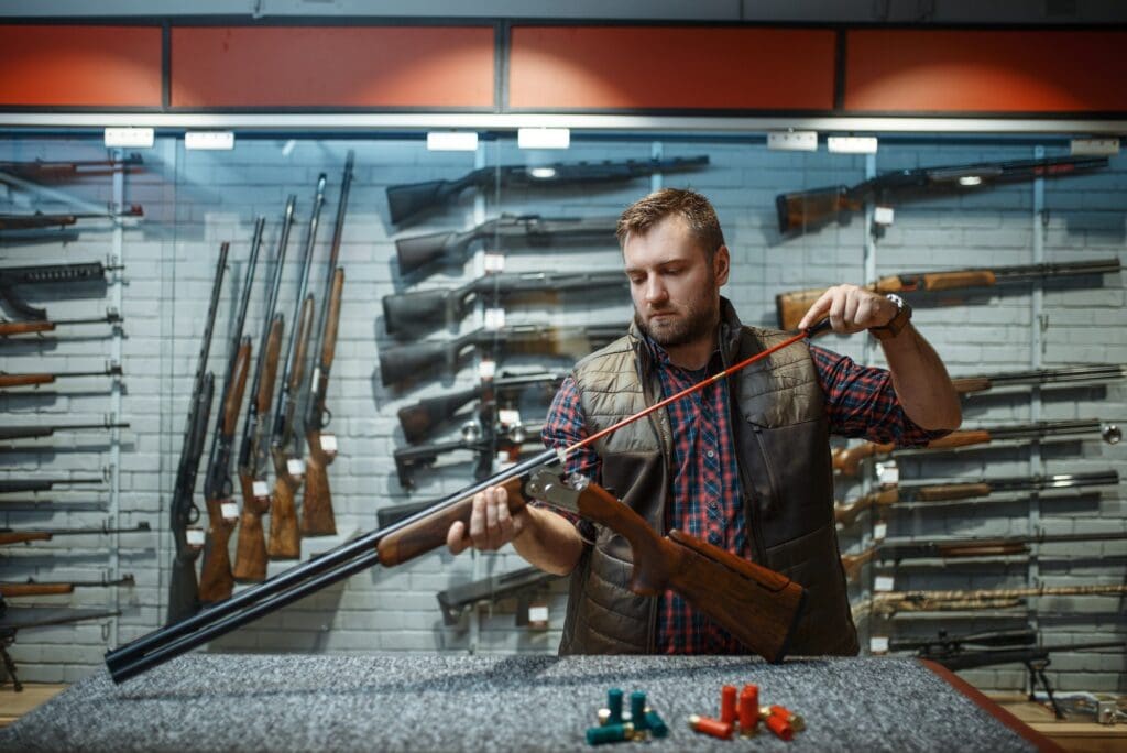Man cleans rifle barrel at counter in gun shop