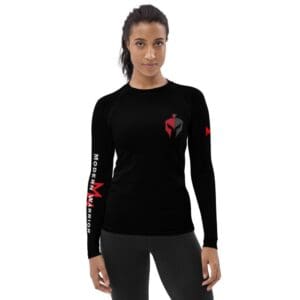 A woman wearing a black long-sleeved MW Combatives Women's Rash Guard with a red logo.