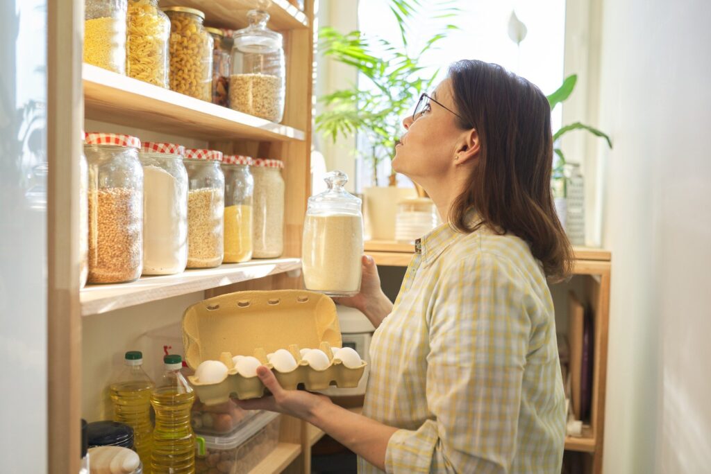Woman in pantry taking products, eggs. Food storage, cooking at home