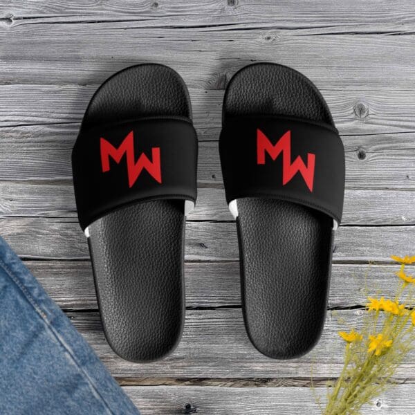 A pair of black and red Modern Warrior Slides featuring the letter m.