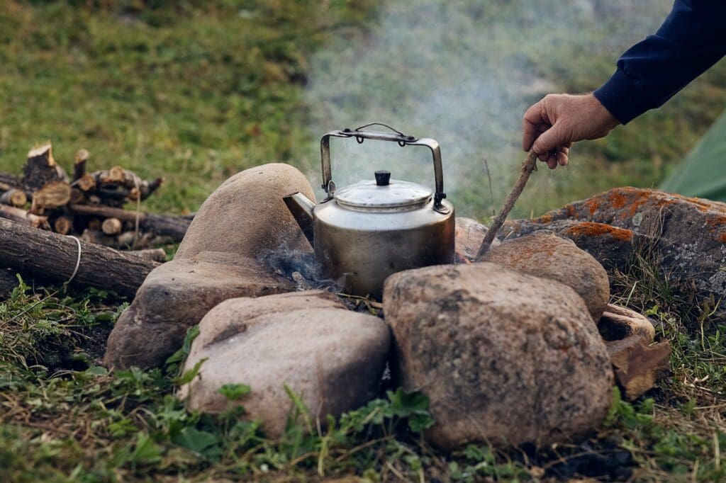 in a camping metal kettle, picnic water is boiled on a campfire