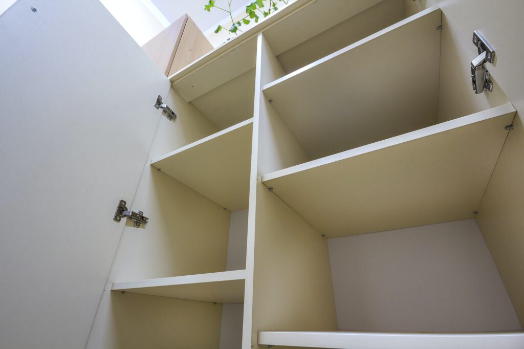 Interior of white plastic cabinet or clothing wardrobe with many empty shelves with open doors