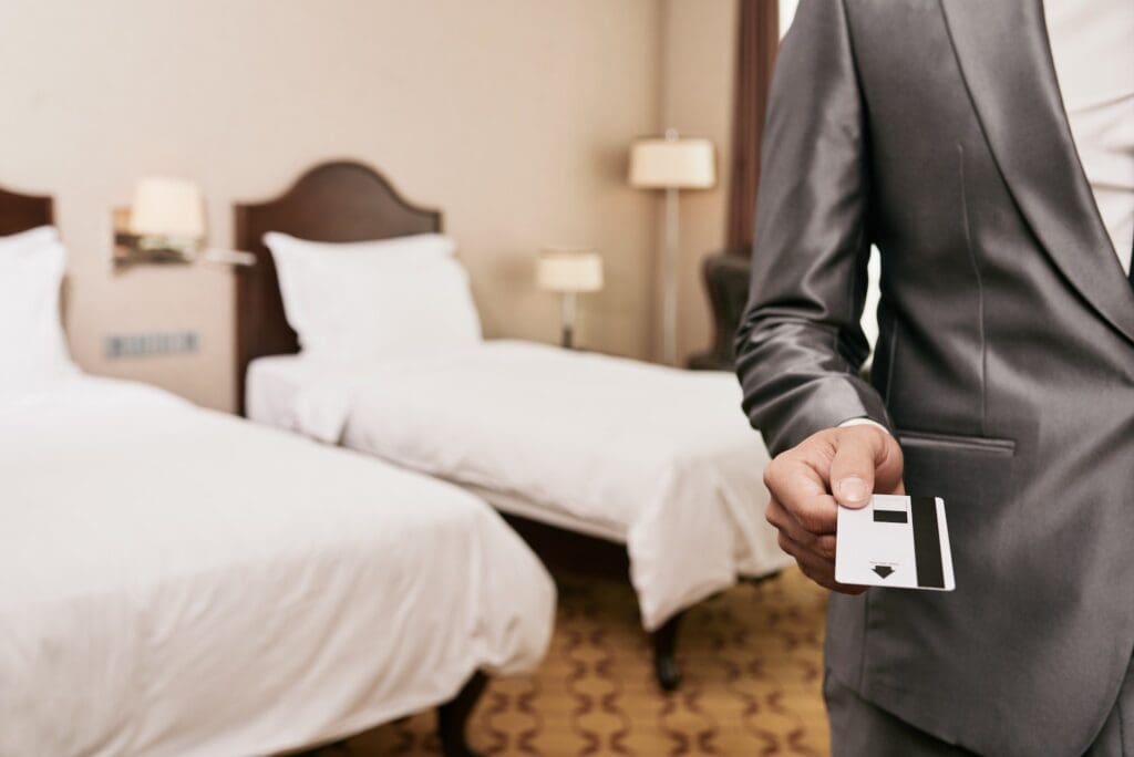 A man in a suit holding a hotel key in a hotel room.