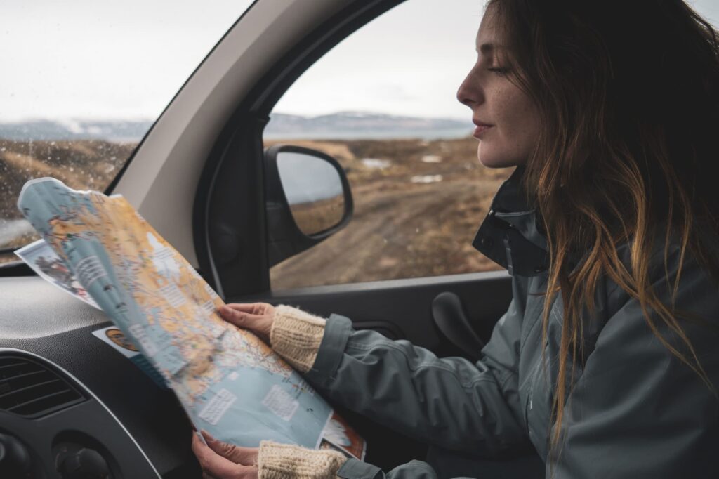 Iceland, young woman in car looking at map