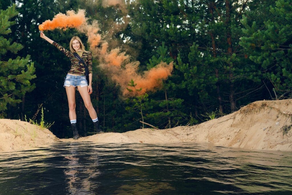 Lost hiker wagging smoke flare to signal for help on outer wood standing by the lake