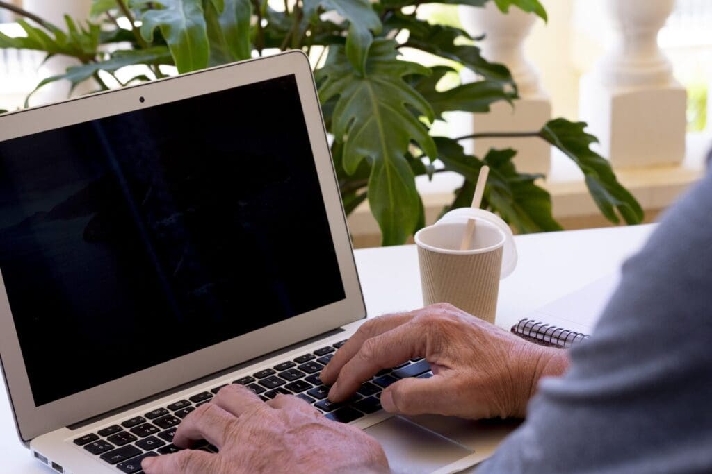 Senior man using laptop, typing on keyboard searching web, browsing information, working