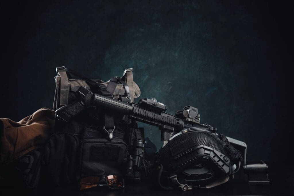 Militray equipment and weapons on a table in dark background