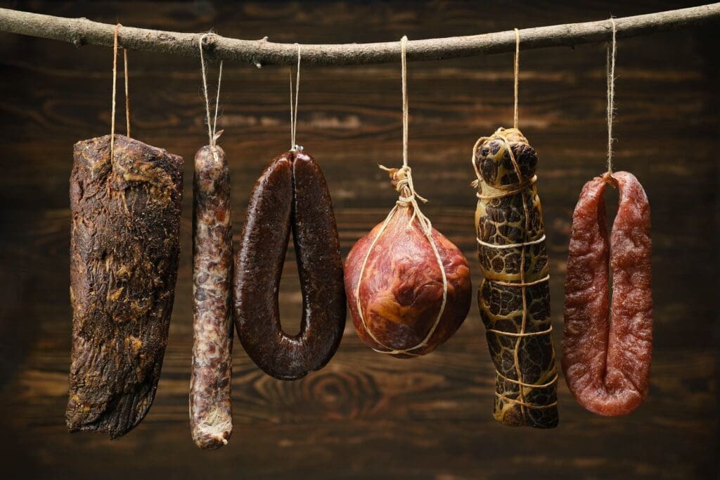 Assortment of dried meat and sausages hanging on a stick