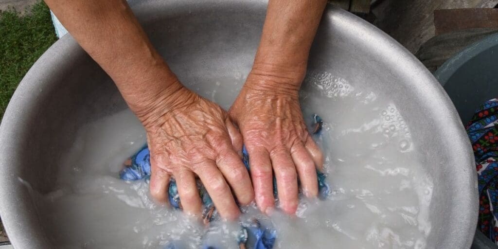 A person mastering the art of hand-washing clothes in a basin of soapy water.