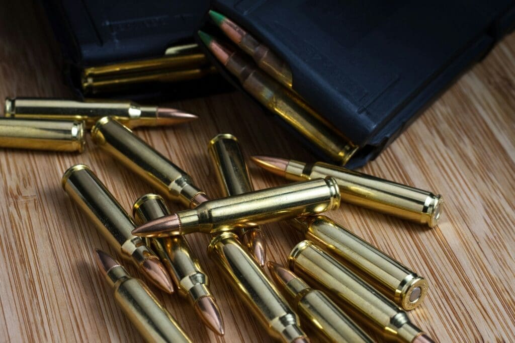 5.56x45mm (.223) AR-15 bullets laid out next to two loaded magazines full of ammunition