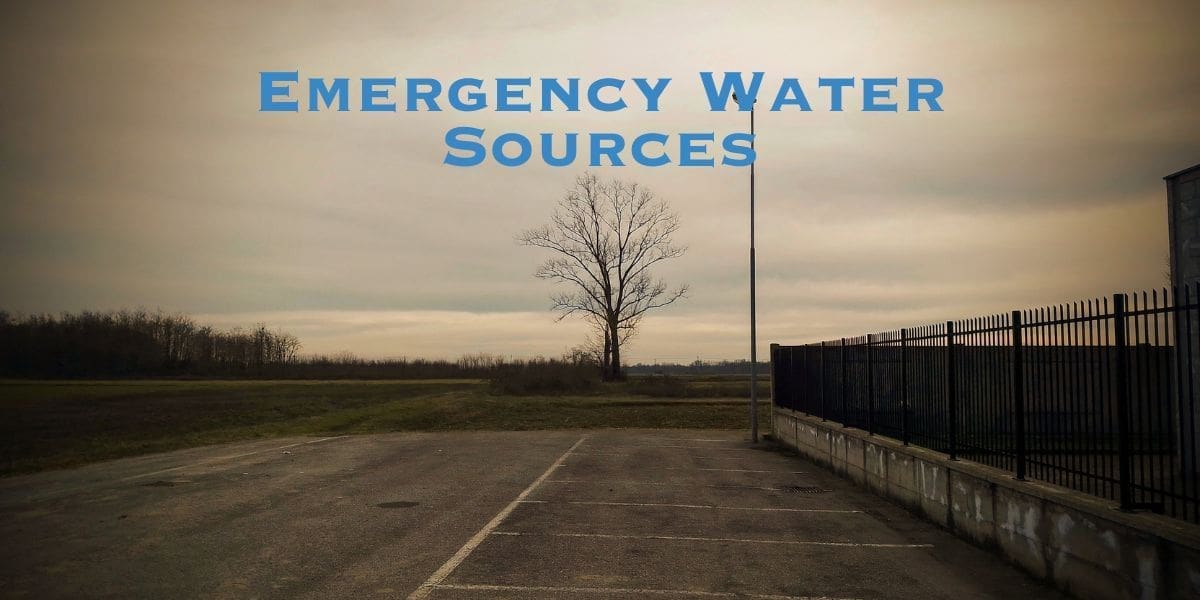 Image of an empty parking lot under a cloudy sky with the text "Emergency Water Sources" overlaid. A lone tree stands in the background next to a fence, highlighting the importance of water sources in emergency situations.