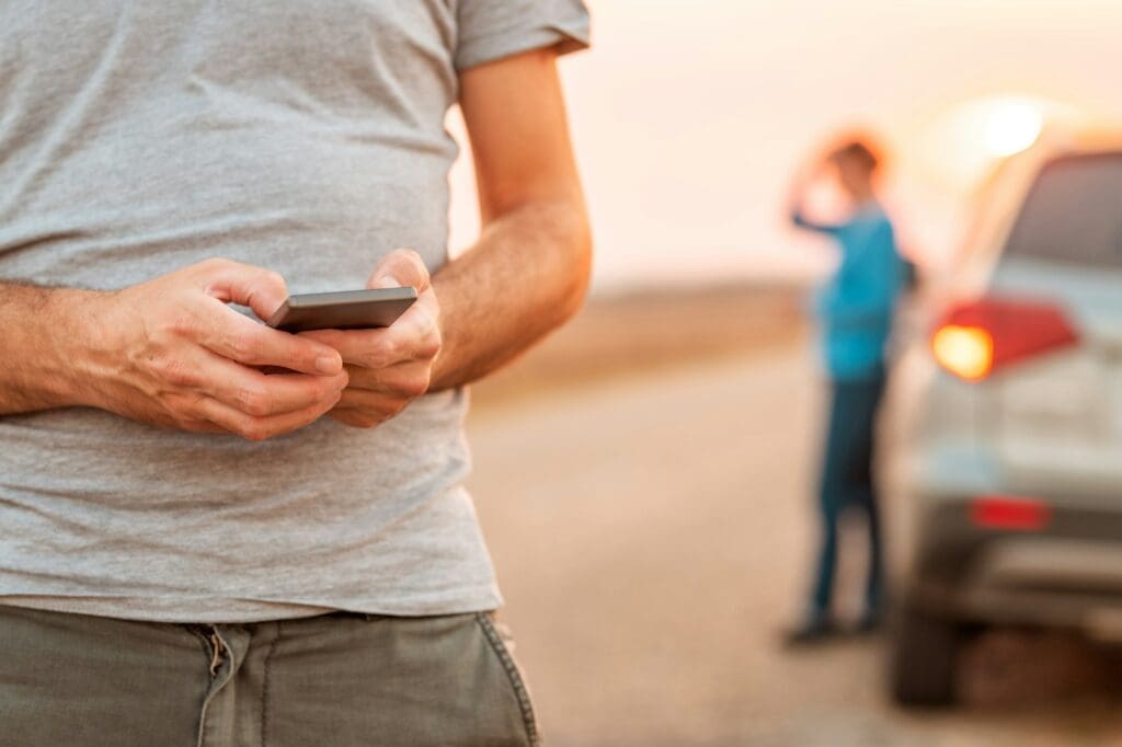 Man texting for roadside assistance after vehicle broke down